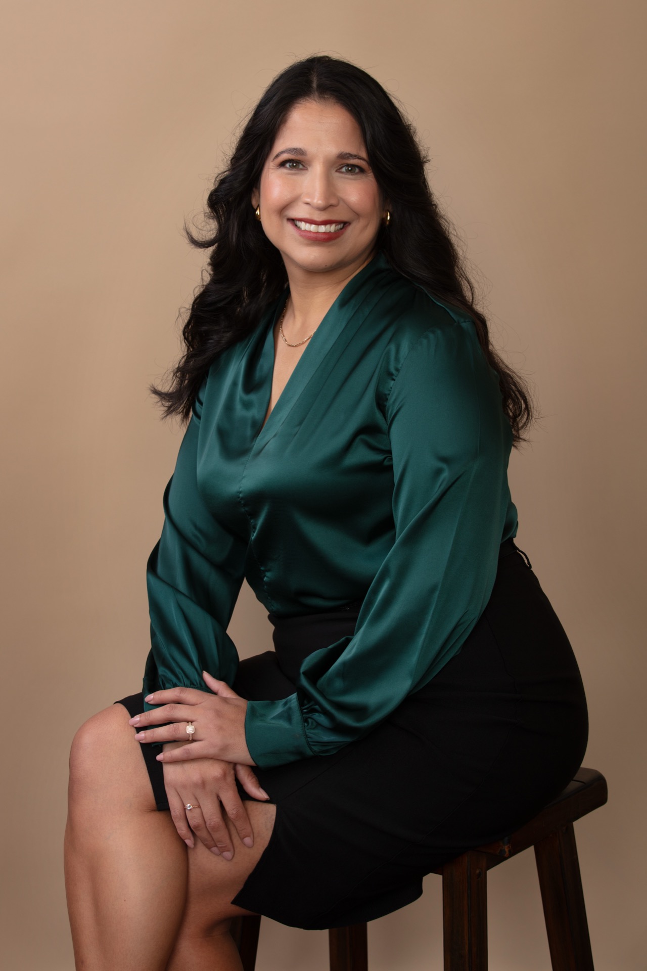 Professional studio headshot, warm tan backdrop